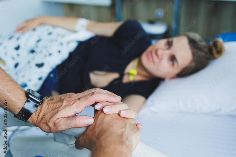 © DSMT - A young woman and a man are sitting in the delivery room and preparing to become parents. The man is holding the hand of his wife who is giving birth to a child. A loving couple in labor together