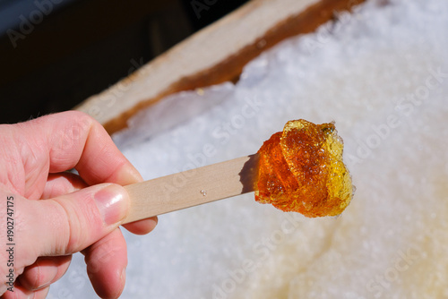 Hand holding a fresh maple taffy stick in winter
