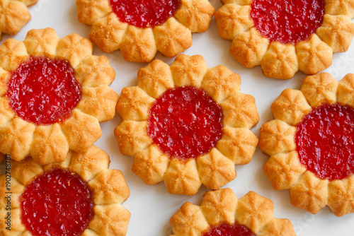 Delicious shortbread cookies with strawberry jelly filling. Flat lay of sweet pastry treat with red jam center. Bakery confectionery background. Photo