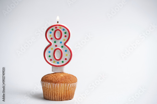 Birthday cupcake with number 8 burning candle on white background.
