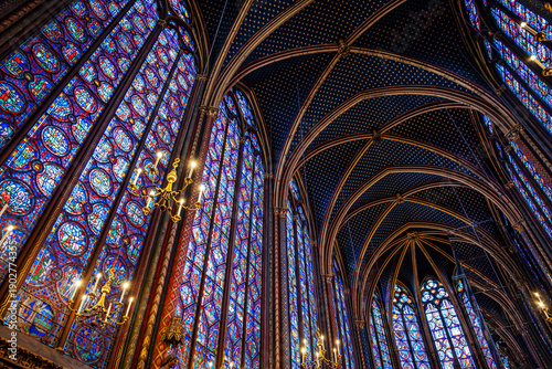 interior of Sainte-Chapelle in Paris featuring towering stained glass windows and a starry vaulted ceiling. Iconic Gothic architecture and medieval French royal heritage in France