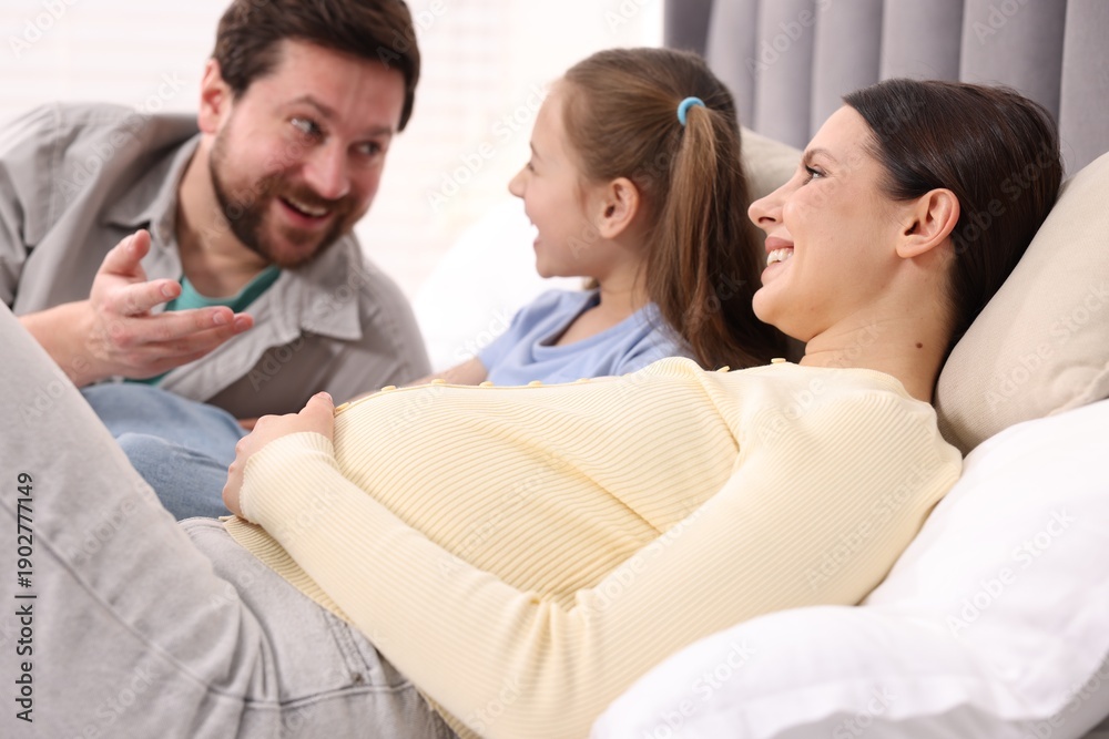 Fototapeta premium Pregnant woman, her husband and daughter on bed at home