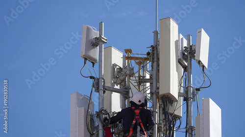 Valokuva Worker wearing safety harness, helmet, maintaining cellular infrastructure, inst