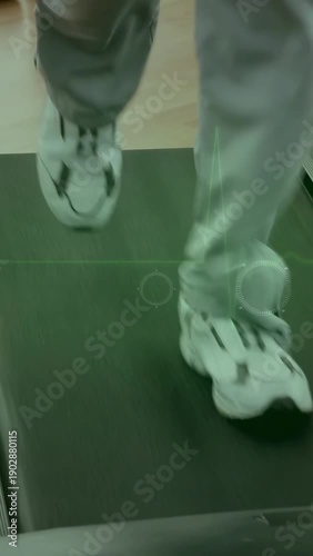 Vertical video: Right foot stepping on treadmill starting feet jogging, hand tapping HUD tracking
