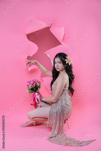 Creative Valentine portrait of beautiful Asian woman with pink roses through torn pape