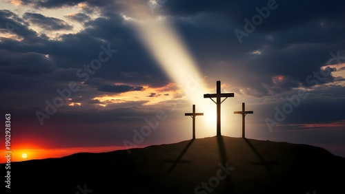 Silhouette of three crosses on a mountain hill under a bright heavenly beam of light during sunset