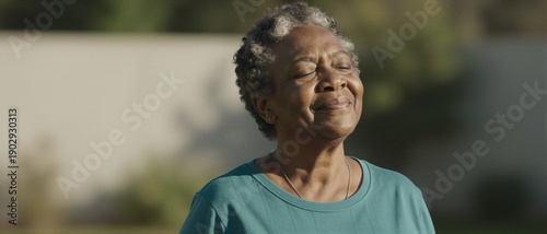 Senior Black woman practicing mindful deep breathing and basking in warm sunlight, focusing on holistic wellness and healthy aging for longevity.