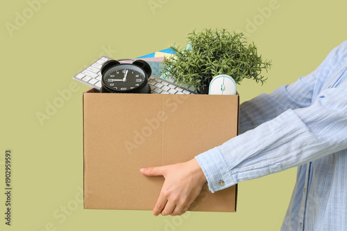 Fényképezés Young woman with office supplies in moving box on green background