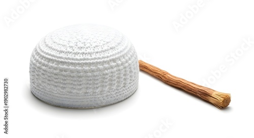 Islamic Prayer Items: A white prayer cap and a Miswak, an organic teeth-cleaning twig, sit together, symbolizing religious devotion and hygiene practices within Islamic culture.