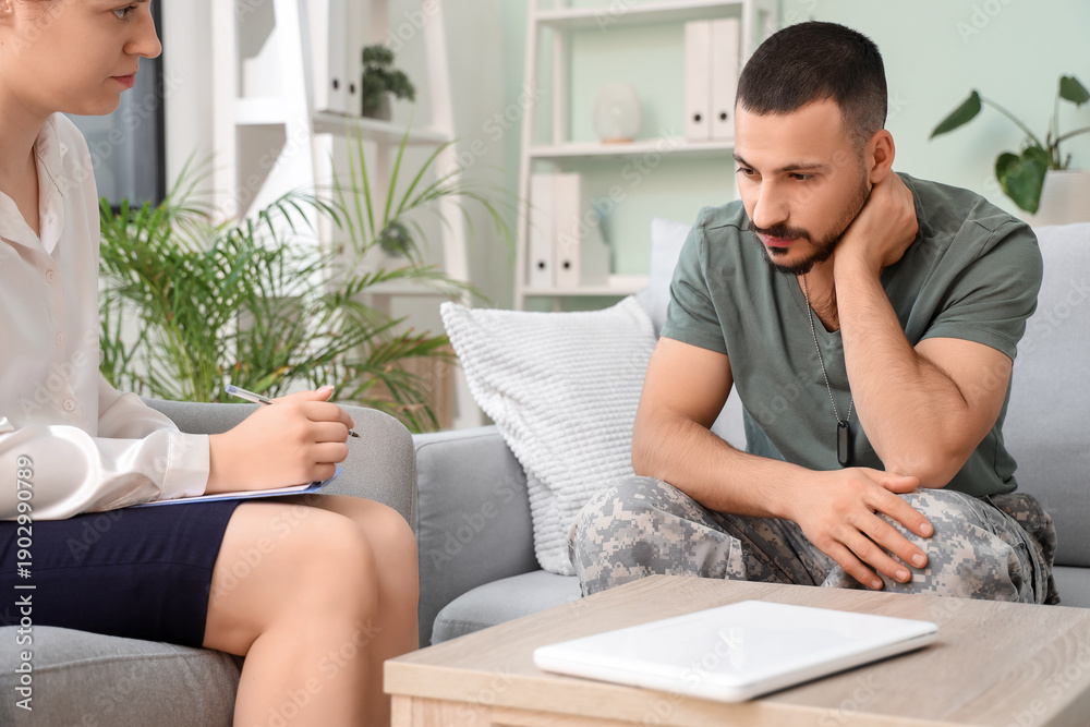 Obraz premium Sad young soldier with PTSD and psychologist sitting in office
