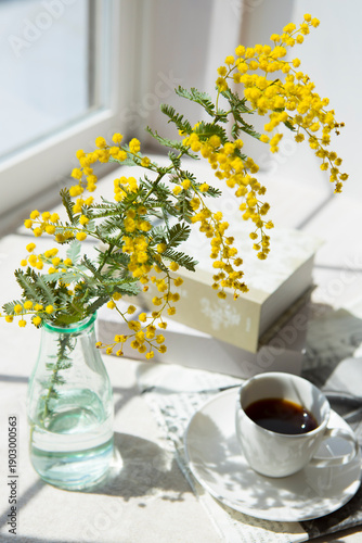 窓辺に置いたコーヒーとミモザの花