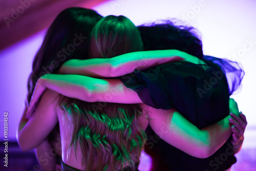 Fotografija Group of friends hugging in bright colored lighting