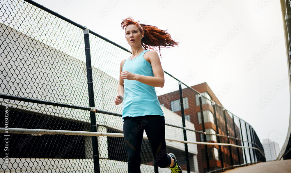 Fototapeta premium Fitness, running and woman in city for training, wellness and challenge for health benefits. Outdoor, person and runner with exercise, morning jog and practice with cardio, bridge and intense workout