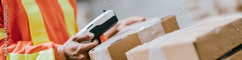 Warehouse worker scanning cardboard boxes using a portable barcode scanner for inventory management in a modern logistics facility with storage background and copy space