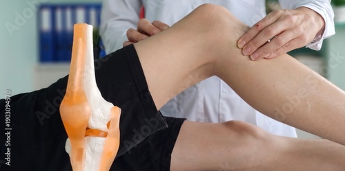 Bild auf Leinwand A physical therapist examines the knee of a teenager sitting on an examination