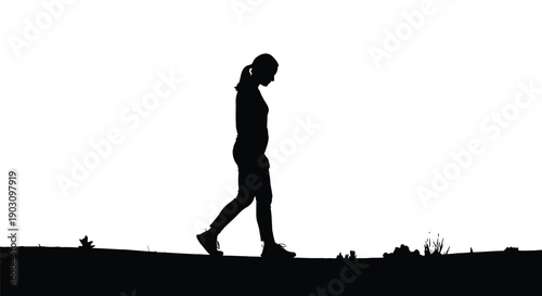Silhouette of a young woman walking alone outdoors with her head slightly bowed down