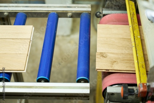 The process of sanding wooden boards on an industrial conveyor in a woodworking plant