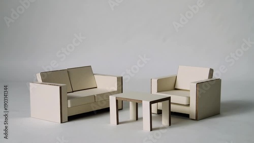 Stop Motion Animation of Cardboard Pieces Folding into Minimalist Sofa and Armchair on White Background.
