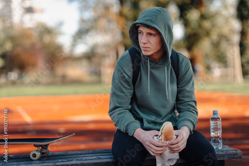 Photography Teenage boy eating sandwich in park contemplating urban life