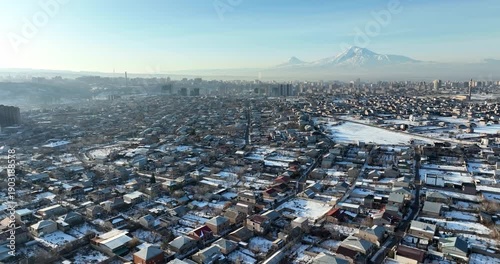 Aerial view of a village in Armenia in winter, with snow-covered roads and cars driving