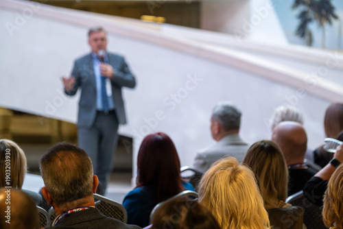 Wallpaper Mural Speaker in suit delivers talk to attentive crowd outdoors near modern venue daylight Torontodigital.ca