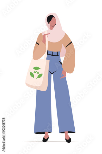 Muslim woman in hijab stands holding a white tote bag over her shoulder with a green leaf symbol and the word ECO printed on it. Concept of eco shopping. Vector. Not AI generated.