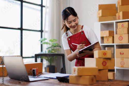 Fotografie Startup small business woman use clipboard checking sme boxs stock on laptop