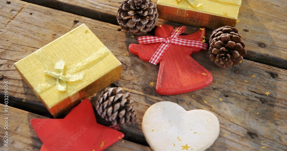 Fototapeta Featuring gold gift boxes and red angel ornament with gingham ribbon on rustic plank, gold confetti