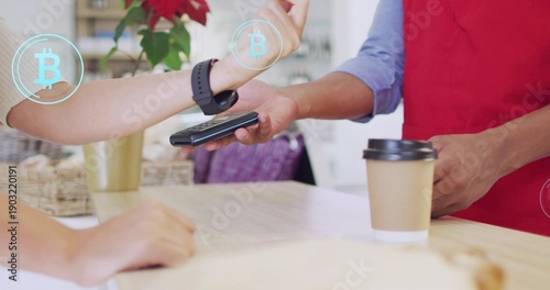 Exchanging customer-barista tapping phone at cafe counter; watch, black-lid cup, Bitcoin, red apron