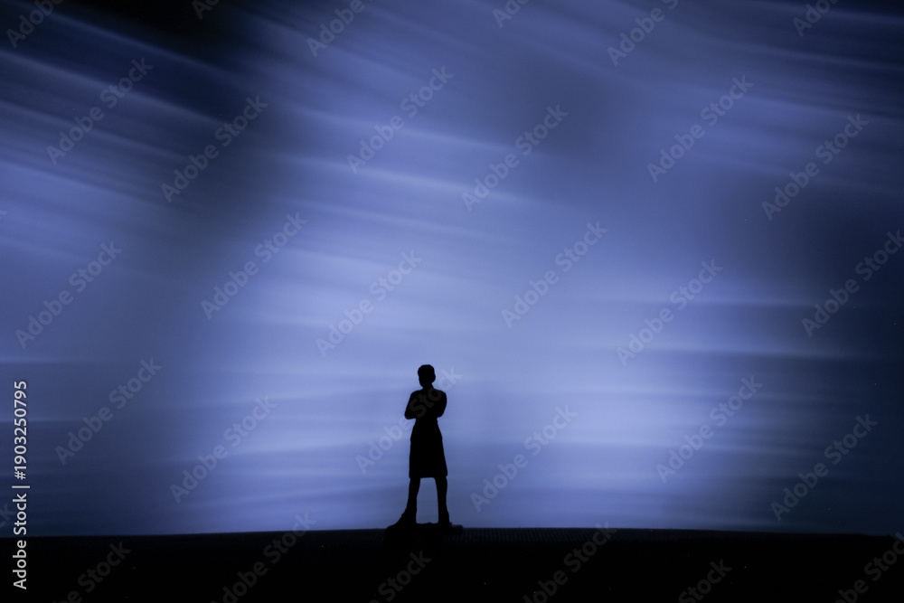 Obraz premium Dramatic silhouette of a person against a purple light