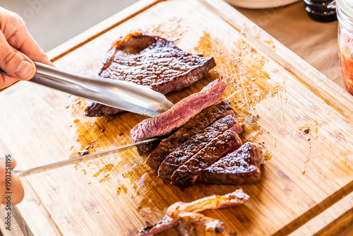 Φωτογραφία Close-up of slicing a grilled beef steak on a wooden cutting board at a campsite