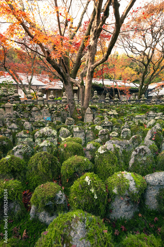 Moss Covered Stone Statues in Japanese Temple During Autumn.Moss-covered stone statues standing in a traditional Japanese temple garden surrounded by autumn foliage. 