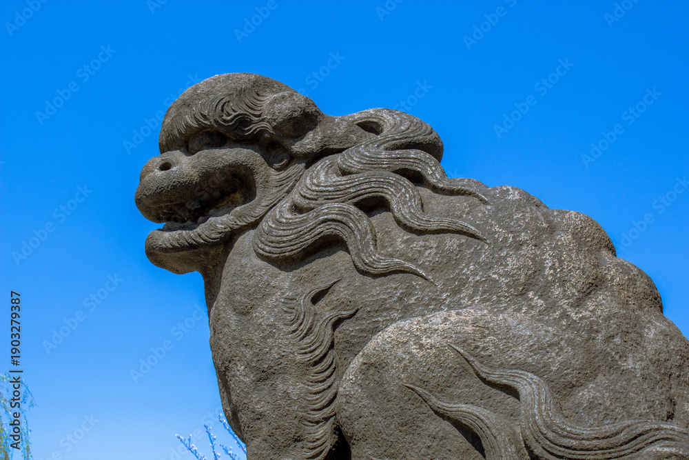 Obraz premium Komainu lion-dog statue against a blue sky with a majestic atmosphere