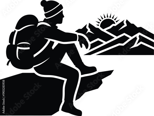 Hiker sitting on a rock formation and looking at the sunrise over a mountain range. 