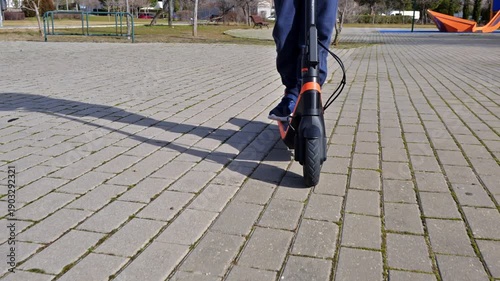 Boy riding a modern electric scooter in a city park