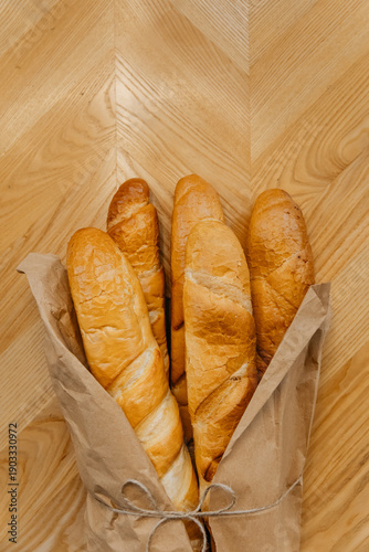 Close-up photo of kraft paper bag with fresh Italian baguettes. French bread bakery
