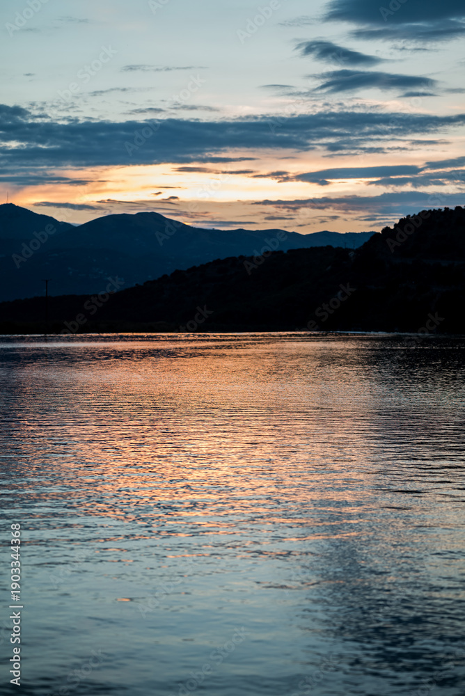 Fototapeta premium Dramatischer Sonnenuntergang hinter den Bergen an einem ruhigen See in Albanien