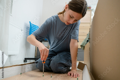 Foto A focused teenage girl assembling a flat pack wardrobe by herself in a room