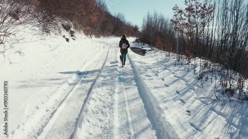 Woman hiking with her dog on a snowy mountain road in winter