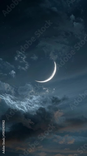 A serene crescent moon shines brightly amidst dramatic clouds in a dark blue night sky viewed from below