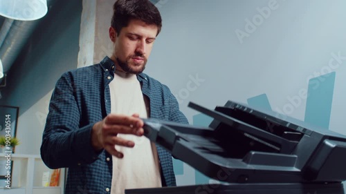Man using a printer in a modern office setting while preparing to scan documents for work