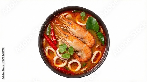Traditional Thai spicy Tom Yum soup with king prawns, squid and chili peppers in a black bowl, isolated on a white background, top view