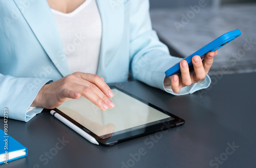 Tableau sur toile A female administrator uses a smartphone and tablet at her office workstation