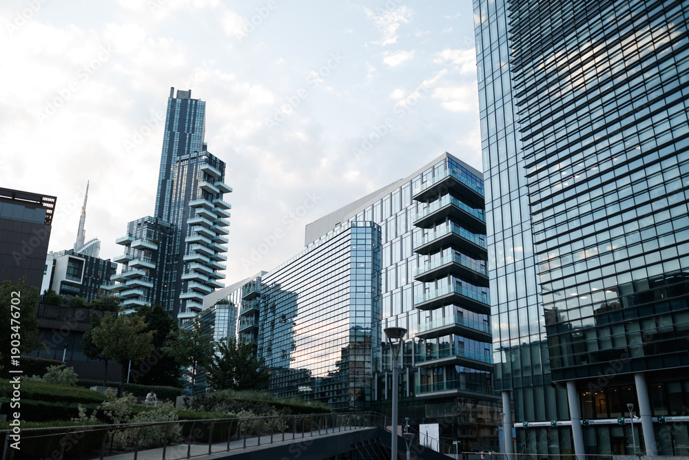 Obraz premium Modern office buildings with glass facades against clear blue sky in Milan. Minimal urban architecture and corporate real estate concept.