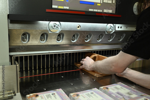 The process of working with an industrial professional paper cutter in the workshop of a printing house