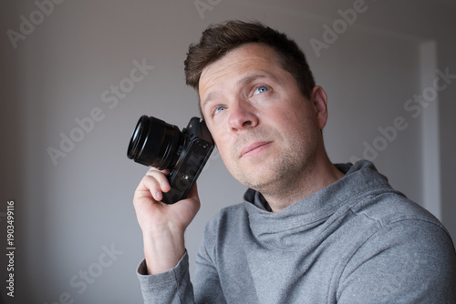 Fotografie Pensive young man with camera doubting about starting photography career