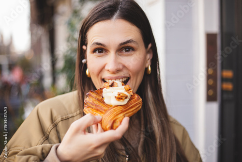 Quadro su tela Stylish young woman biting crispy danish pastry with delicate cream at third wav