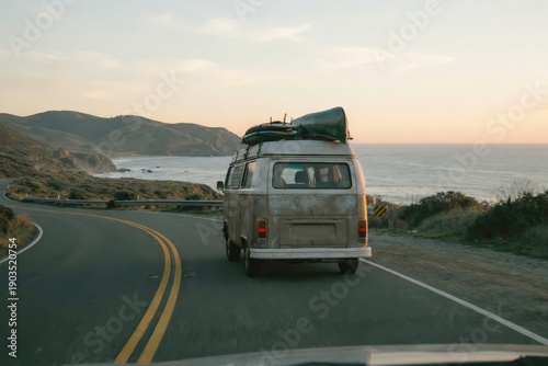 Vintage camper van driving on a scenic coastal road at sunset with surfboards on top. Adventure and summer travel concept