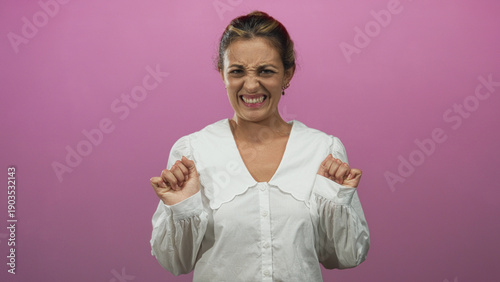 Billede på lærred Woman wincing with hands raised and clenched fingers, scrunched face and pursed mouth in studio with pink wall; disgust