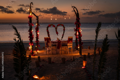 Obraz na plátně A romantic dinner table for two set on a beach at sunset with flower arches and decorative lights